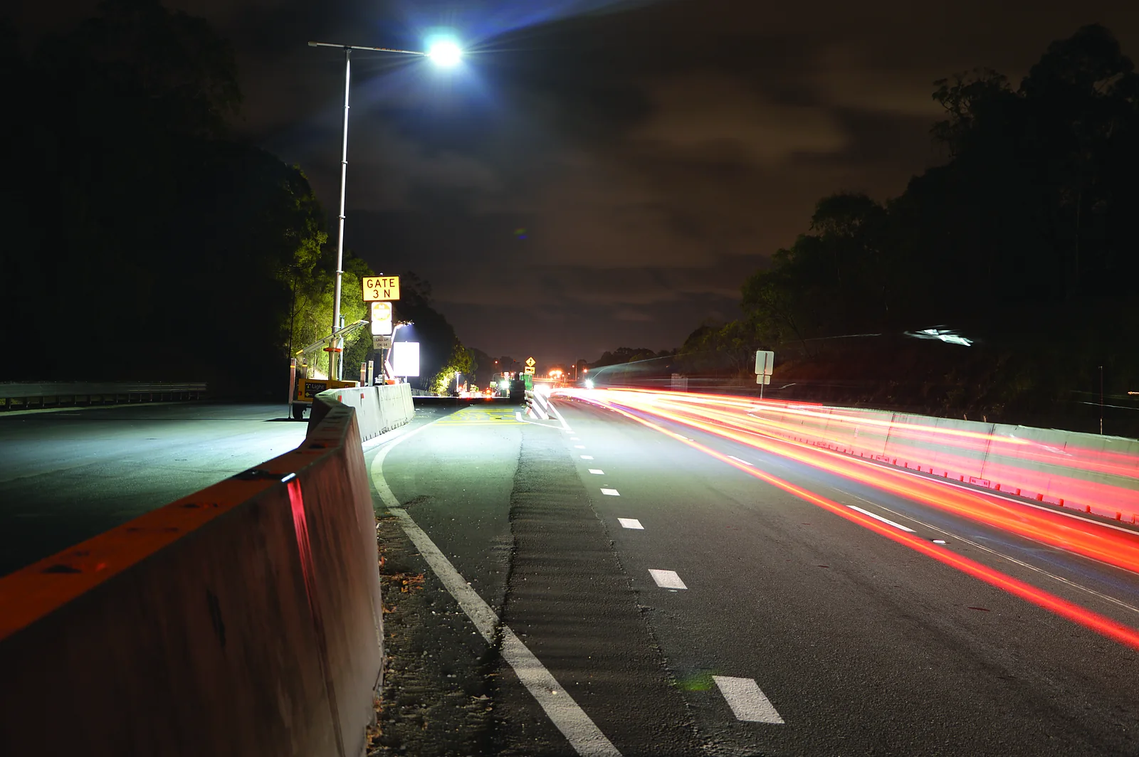 A T Light unit lighting a highway at night, with traffic light trails